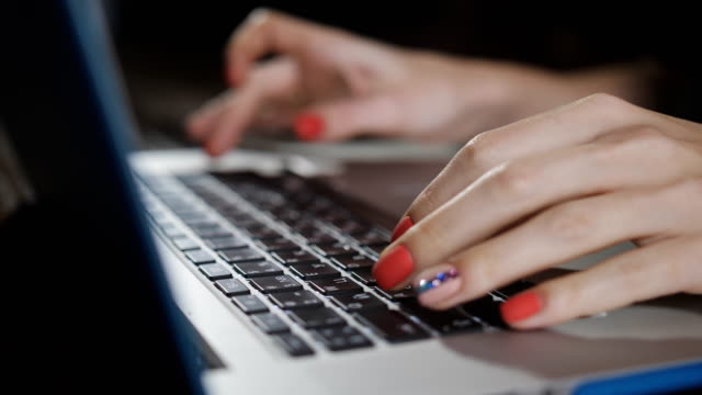 Young-woman-typing-on-laptop-keyboard,-close-up.-Girl-with-a-beautiful-manicure-prints-the-text-on-the-laptop-keyboard.