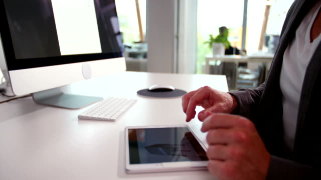 Hand-of-business-man-swiping-tablet-in-office