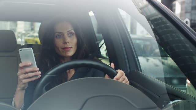 Attractive-Smiling-Business-Woman-Using-Mobile-Phone-in-a-Car