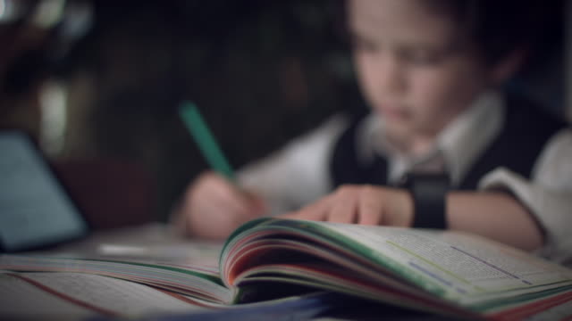 4K-Hi-Tech-Shot-of-a-Child-Doing-Homework,-focus-changing-to-book