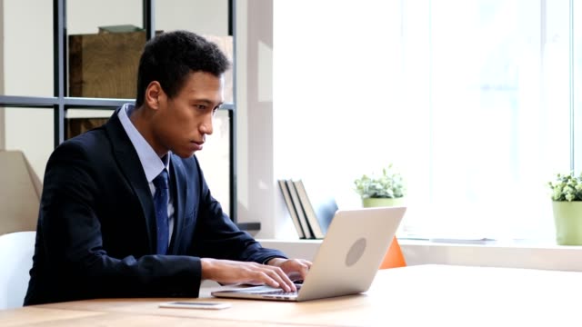 Black-Businessman-Upset-by-Loss-while-Working-on-Laptop