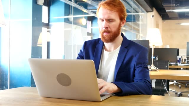 Hombre-pensando-y-trabajando-en-ordenador-portátil,-pelos-rojos