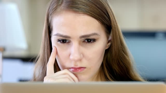 Woman-Thinking-and-Working-on-Laptop
