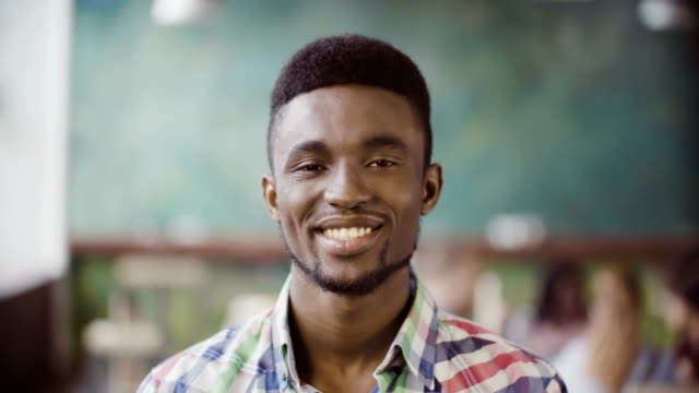 Retrato-de-joven-empresario-de-éxito-africano-en-oficina-ocupada.-Guapo-hombre-mirando-a-cámara-y-sonriendo-Inicio