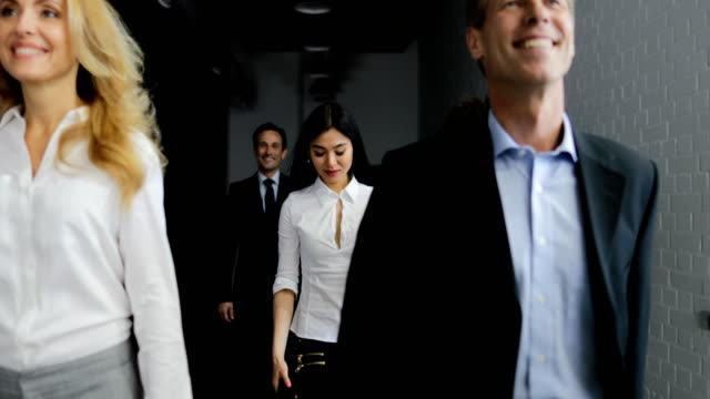 Team-von-Geschäftsleuten-zu-Fuß-im-Büro-während-asiatische-Geschäftsfrau-Antwort-Anruf