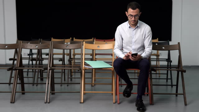 business-man-in-empty-conference-room-touching-smartphone