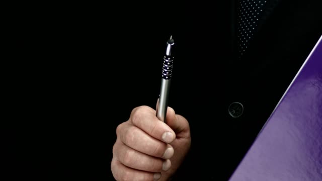 Businessman-Holding-A-Purple-Folder-Performs-Gestures-With-A-Pen.