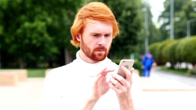Using-Smartphone-for-Online-Browsing,-Man-with-Red-Hairs,-Outdoor