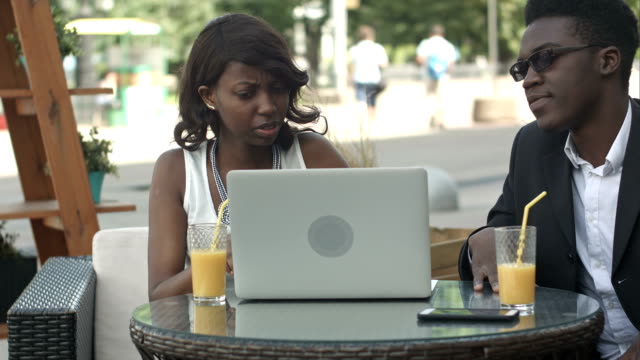 Hombre-en-traje-formal-de-explicar-estrategia-de-negocios-a-su-colega-femenina-africana-usando-laptop-durante-la-reunión,-dando-alta-cinco-en-un-café