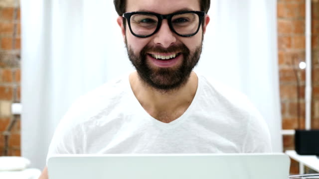 Retrato-de-sonriente-hombre-de-barba-positiva-trabajando-en-equipo-portátil