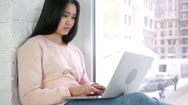 Mujer-afroamericana-joven-pensativa-trabajando-en-ordenador-portátil,-mira-por-la-ventana
