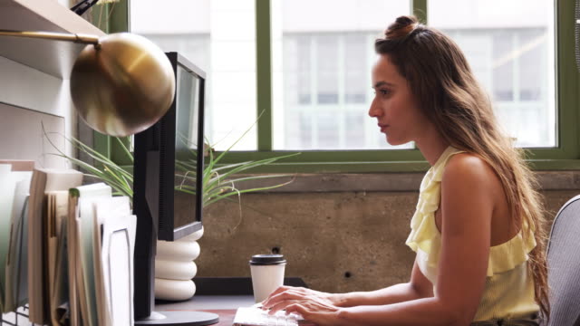 Junge-weiße-Frau,-die-mit-Computer-in-einem-Büro,-Seitenansicht