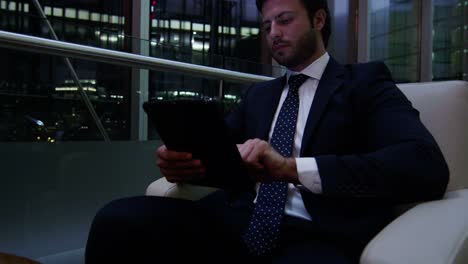 Arabic-male-business-traveller-tablet-night-hotel-atrium