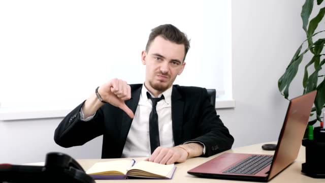 Young-businessman-in-suit-sitting-in-office-and-showing-thumbs-up-sign-60-fps