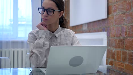 Thinking-Hispanic-Woman-Working-on-Laptop,-Sitting-In-Office