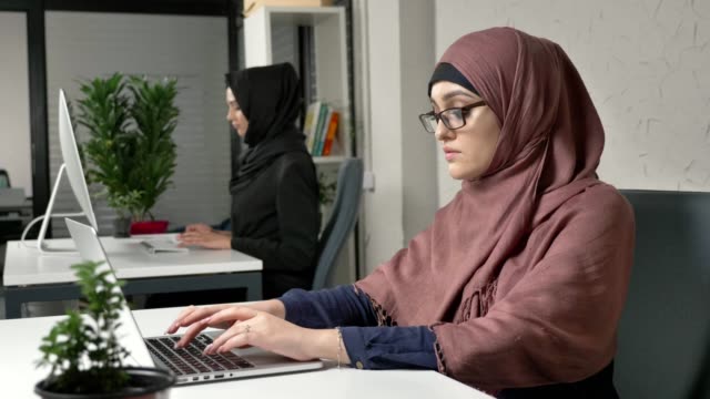Ein-junges-schönes-Mädchen-in-rosa-Hijab-zieht-ihre-Brille-und-massiert-die-Brücke-der-Nase.-Müde-Augen.-Arabische-Mädchen-im-Büro.-60fps