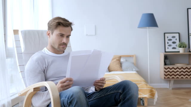 Erwachsener-Mann-Lesung-Dokumente-auf-entspannenden-Stuhl-sitzend