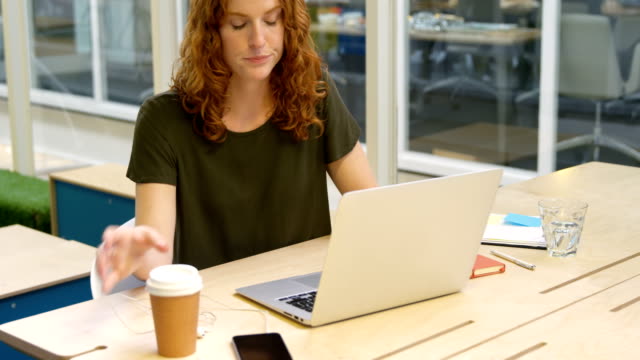 Mujer-de-negocios-usando-laptop-teniendo-café-4k