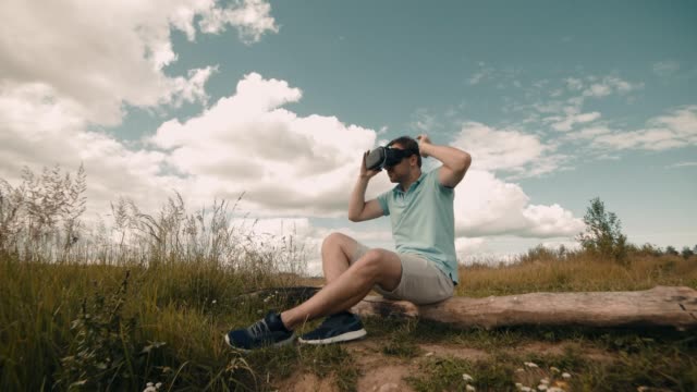 Mensch-in-der-virtuellen-Realität-Kopfhörer-sitzt-an-Natur.-Männliche-beobachten-video-360