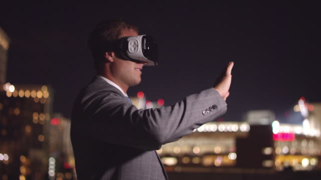 Young-business-man-wearing-VR-headset-at-night-swiping-screen-with-hand-gestures