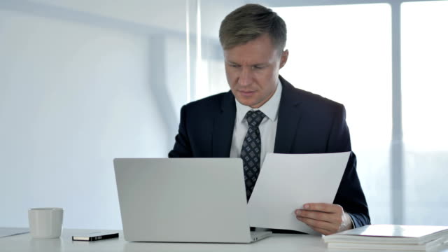 Businessman-Working-on-Documents-and-Laptop