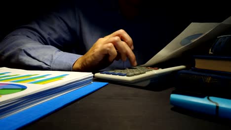 Hombre-de-negocios-utiliza-la-calculadora-para-comprobar-el-informe-financiero.