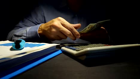 Hombre-contando-billetes-de-dólar-y-usando-calculadora.-Préstamos-en-la-oficina.