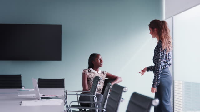 Two-Casually-Dressed-Businesswomen-Having-Informal-Meeting-In-Modern-Boardroom-Shot-In-Slow-Motion