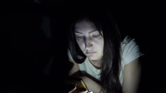 Young-woman-in-the-dark-at-night-sits-with-a-phone-in-social-networks