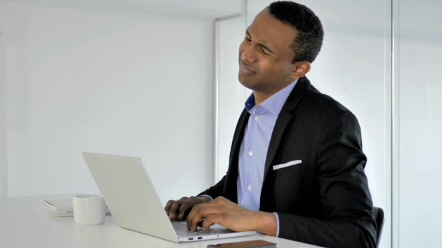 Lässige-afroamerikanischer-Geschäftsmann-mit-Nackenschmerzen-auf-Laptop