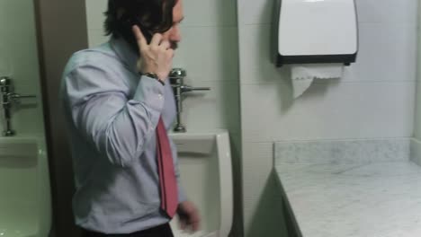 Gerente-enojado-gritando-en-el-teléfono-móvil-en-los-lavabos-de-lugar-de-trabajo