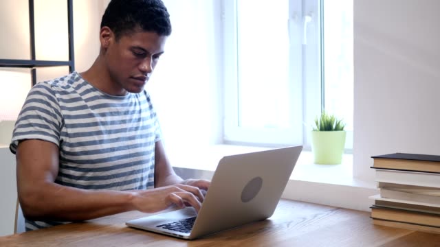 Junge-schwarze-Mann-arbeitet-auf-Laptop