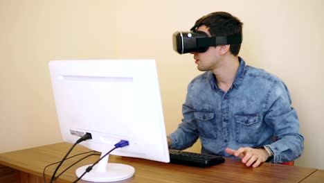 Young-programmer-works-with-VR-glasses-on-while-sitting-near-his-personal-computer.-Shot-in-4K.