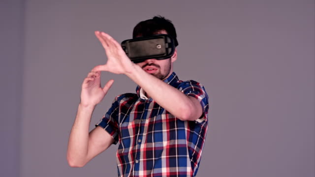 Excited-young-man-in-VR-glasses-actively-gesturing-in-the-air