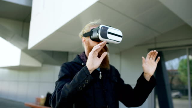 Dolly-de-joven-barbudo-hombre-con-casco-de-realidad-virtual-360-experiencia-de-VR-y-tomar-de-gafas-sonriente-al-aire-libre