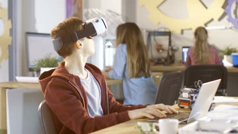 In-einem-Computer-Wissenschaft-Klasse-jungen-tragen-Virtual-Reality-Kopfhörer-arbeitet-an-einem-Programmierung-Projekt.