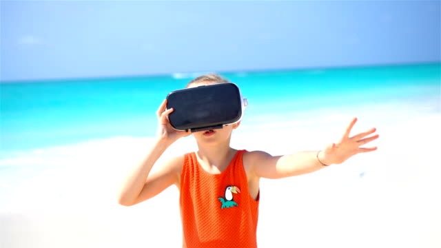 Gafas-niño-niña-linda-usando-realidad-virtual-VR.-Adorable-chica-mire-las-gafas-virtuales-en-Playa-Blanca