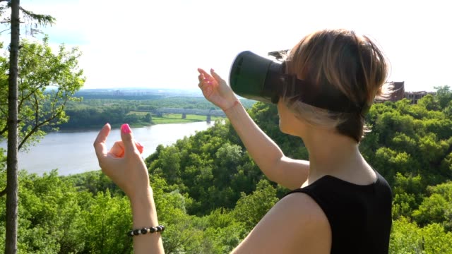 Junge-Frau-nutzt-Head-mounted-Display-im-Park.-Spielen-Spiel-mit-VR-Helm-für-Smartphones
