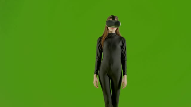 Attractive-girl-young-fashion-model-wearing-a-VR-headset-shot-in-green-screen-studio-.-Interactive-futuristic-gesture-.-Medium-s
