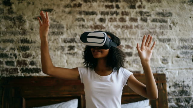 Lockige-afroamerikanische-Frau-Erfahrungen-mit-VR-360-Kopfhörer-Brille-der-virtuellen-Realität-zu-Hause