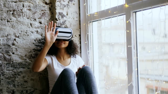 Mujer-afroamericana-rizada-obteniendo-experiencia-utilizar-VR-360-auricular-gafas-de-realidad-virtual-en-casa