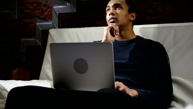 Pensive-Thinking-African-Man-Working-on-Laptop-at-Night
