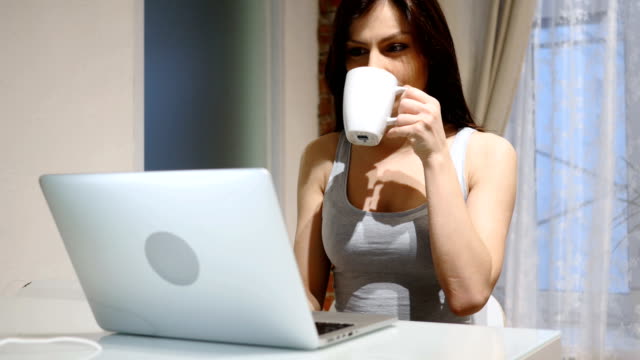Porträt-der-jungen-Frau-trinken-Kaffee-und-arbeiten-am-Laptop