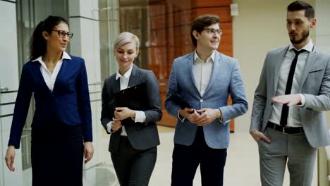 Stedicam-shot-group-of-young-business-people-talking-and-walking-in-office-lobby