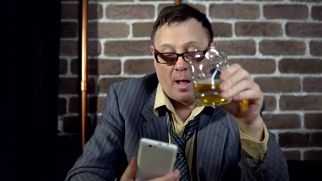 Businessman-using-telephone-and-drinking-alcohol-indoors-with-brick-wall.
