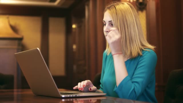 Mujer-joven-mirando-en-la-pantalla-del-ordenador-portátil-y-digitar-en-el-teclado