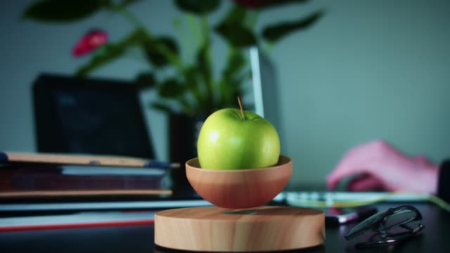 Dispositivo-de-levitación-de-4K-con-manzana-en-oficina-corporativa
