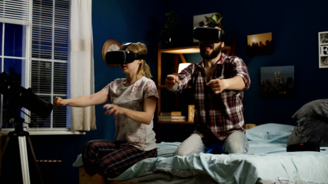 Couple-in-VR-glasses-having-fun-on-bed