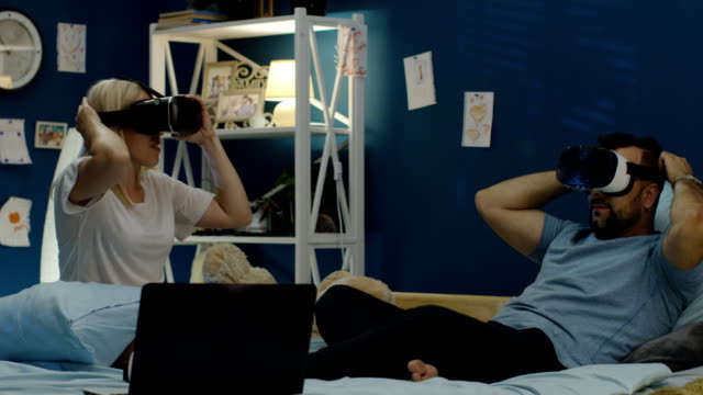 Couple-in-VR-glasses-chilling-on-bed