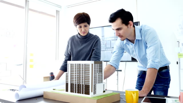 Architect-talking-to-building-project-together.-Attractive-architect-or-engineer-is-concentrating-as-he-examines-the-new-building-project-development.